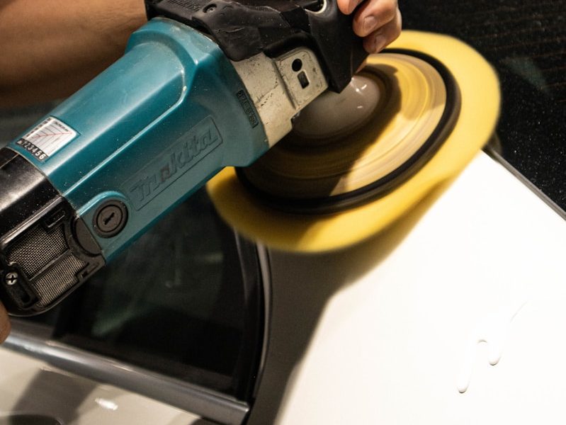 a person sanding a car with a sander
